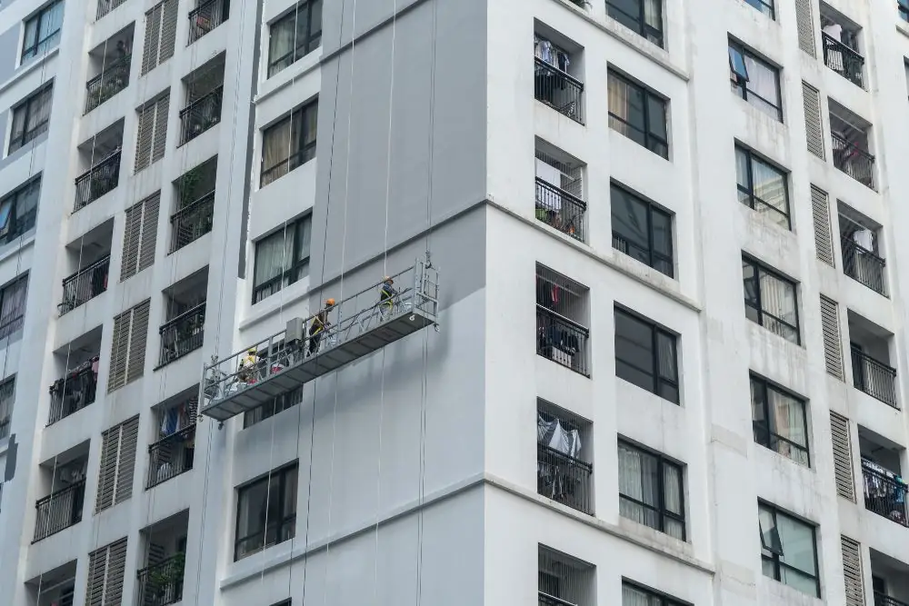Equipe executando serviço em fachada de edifício com plataforma suspensa