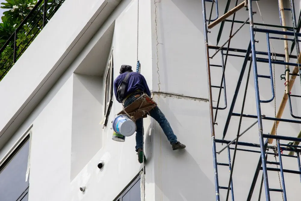 Profissional executando restauração e pintura de fachada em edifício